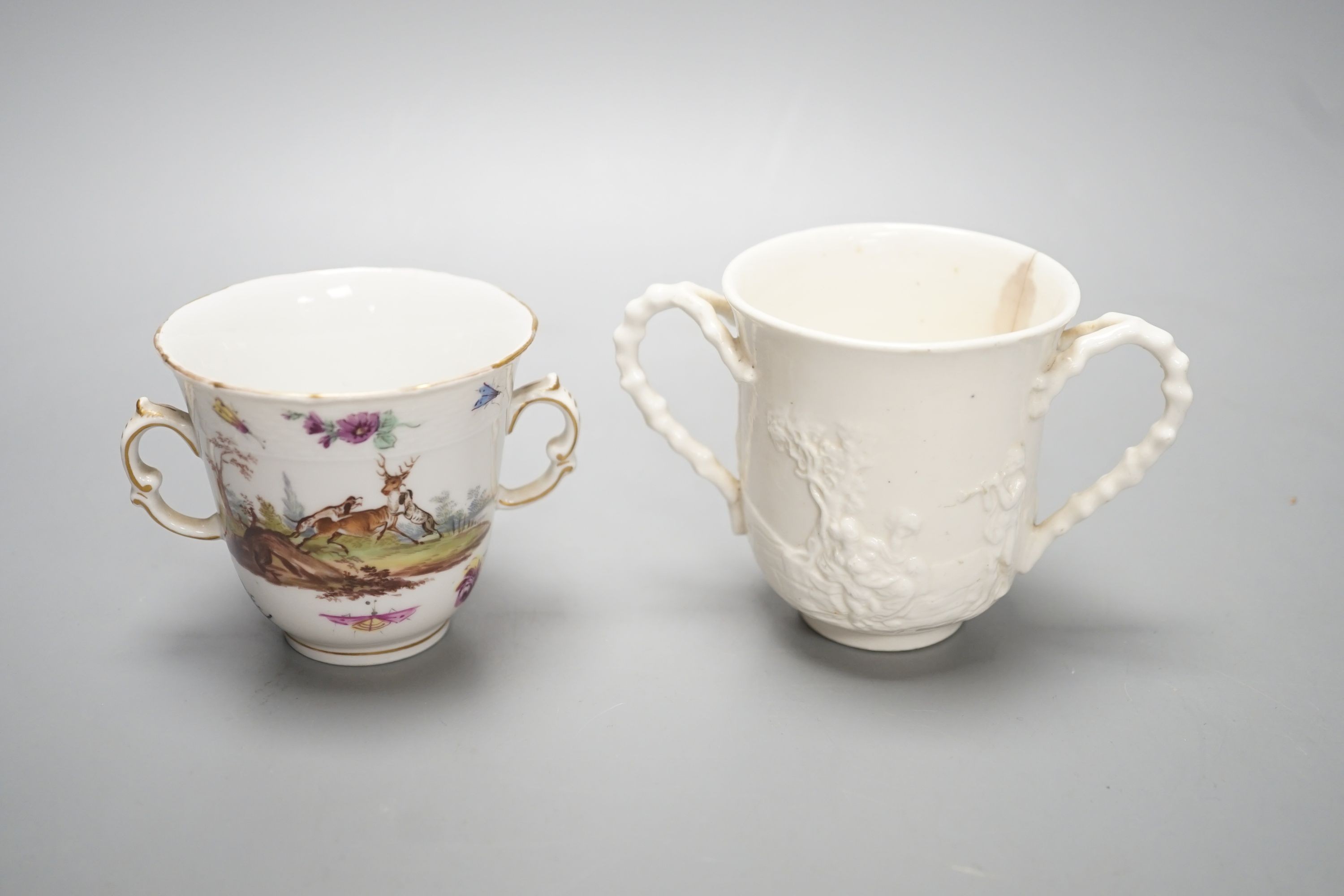 A late 18th / early 19th century Berlin two handled chocolate cup, 7cm high, painted with hunting scenes and an 18th century Doccia two handled chocolate cup moulded in Istoriato style.